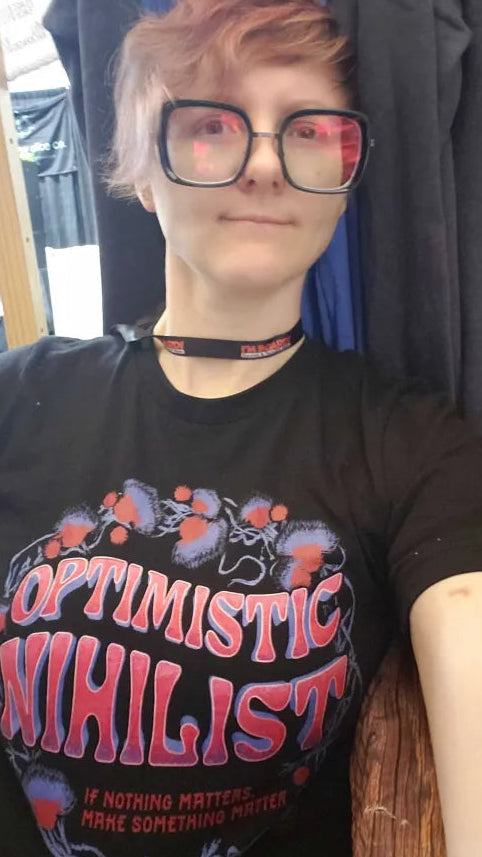 Enby wearing the Optimistic Nihilist shirt