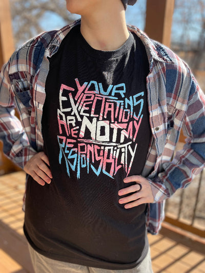 model wearing "Your Expectations Are Not My Responsibility" graphic tee in trans pride colors
