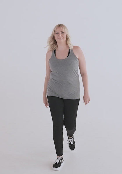 Video of white woman with blond hair showing the fit of the racerback tank top. It hugs curves, has flat sensory friendly seams and hems, is very light weight fabric. Neckline is at a medium, doesn't show a lot of cleavage, but is low enough to frame a necklace.