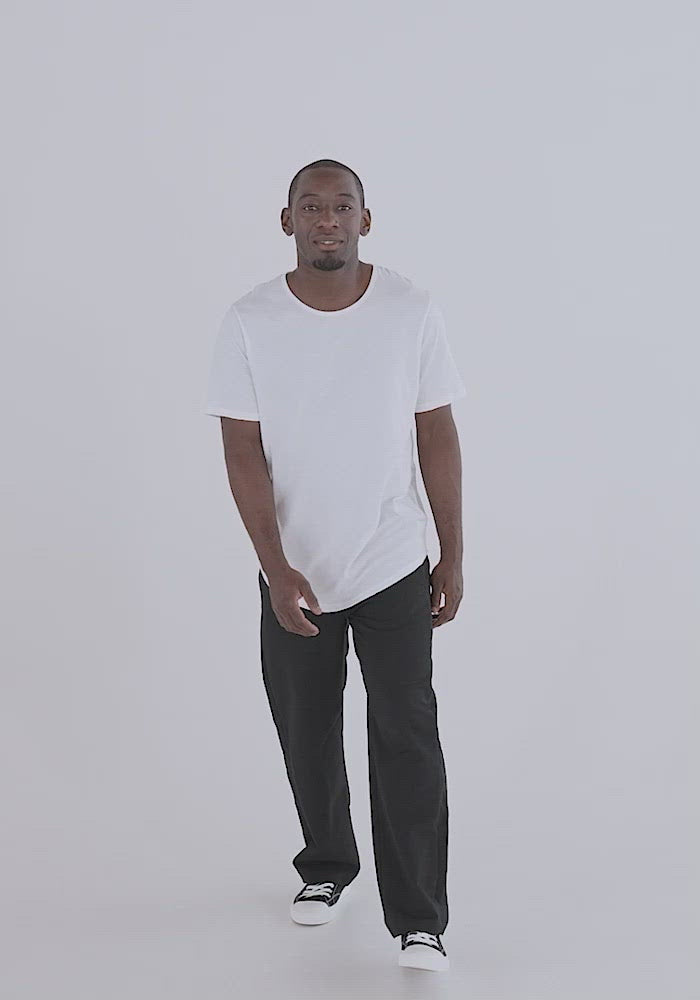 Video of black man showing how the Curved hem shirt fits.  The curved hem curves down in front and back  creating a tailored look. The hem flows passed even low rise pants